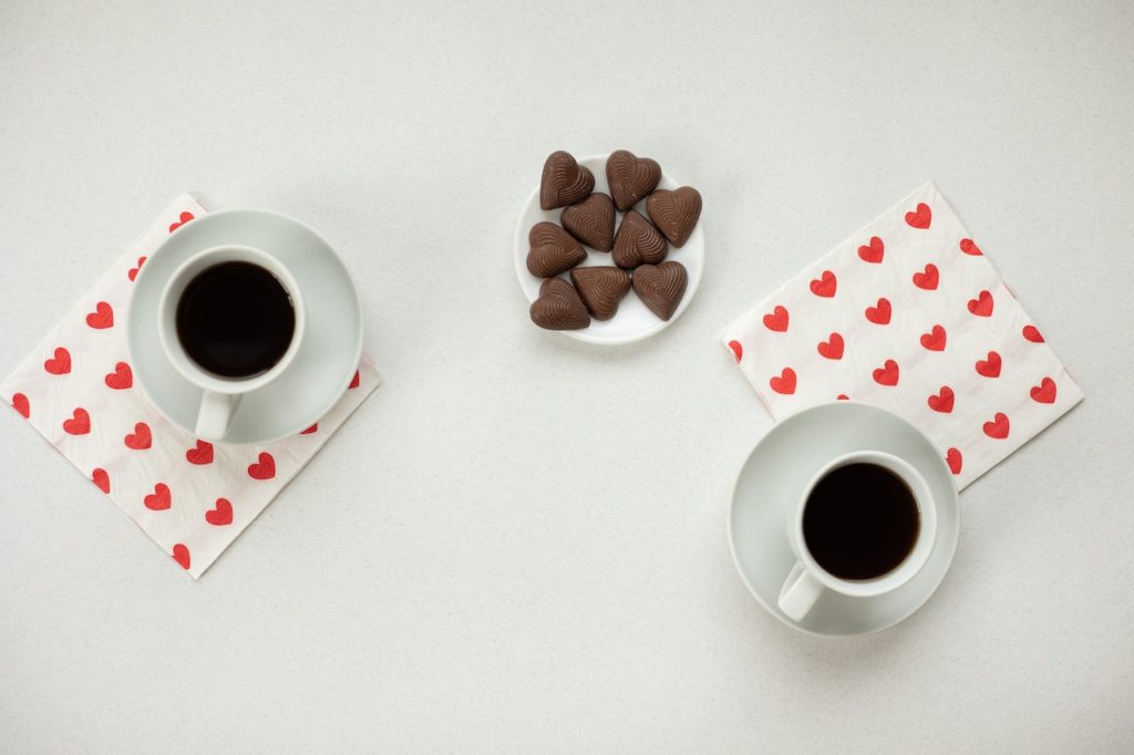 Coffee and candies near napkins with hearts