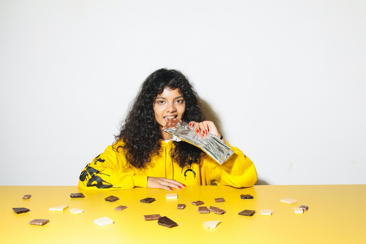 Curly-Haired Woman Eating a Chocolate Bar

