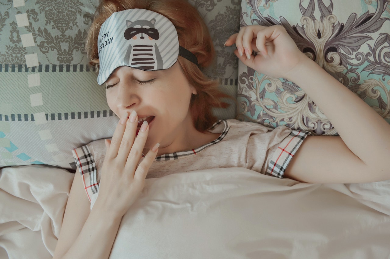 Sleepy woman yawning on bed
