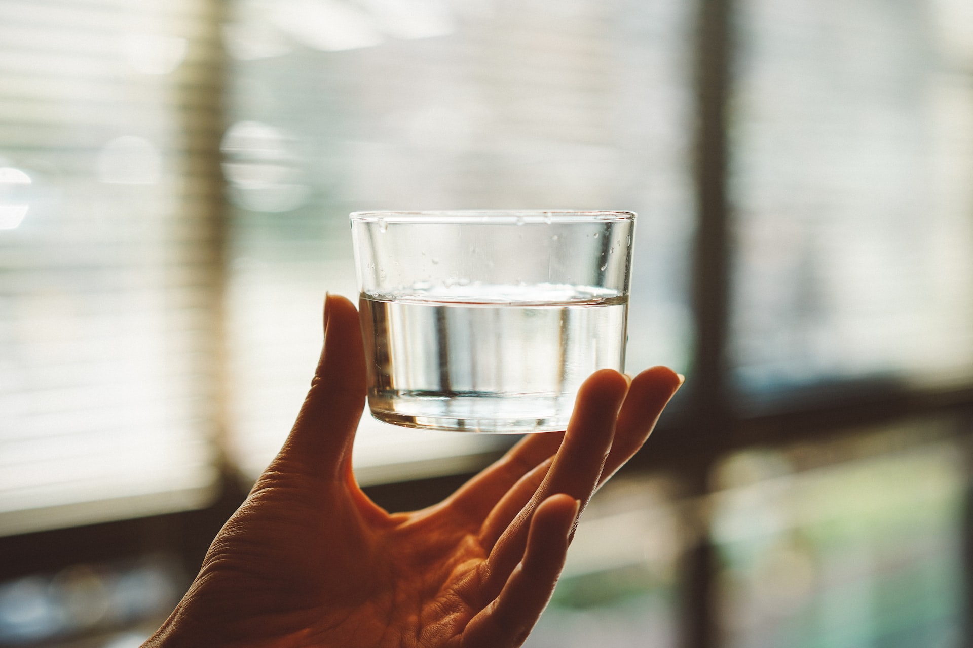 A person holding a clear glass of water