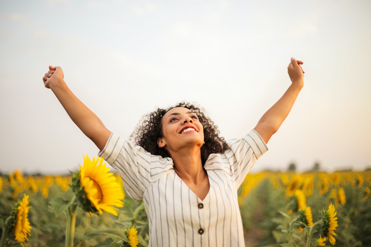 Photo Of Woman With Hands Up Standing On Sunflower Field

